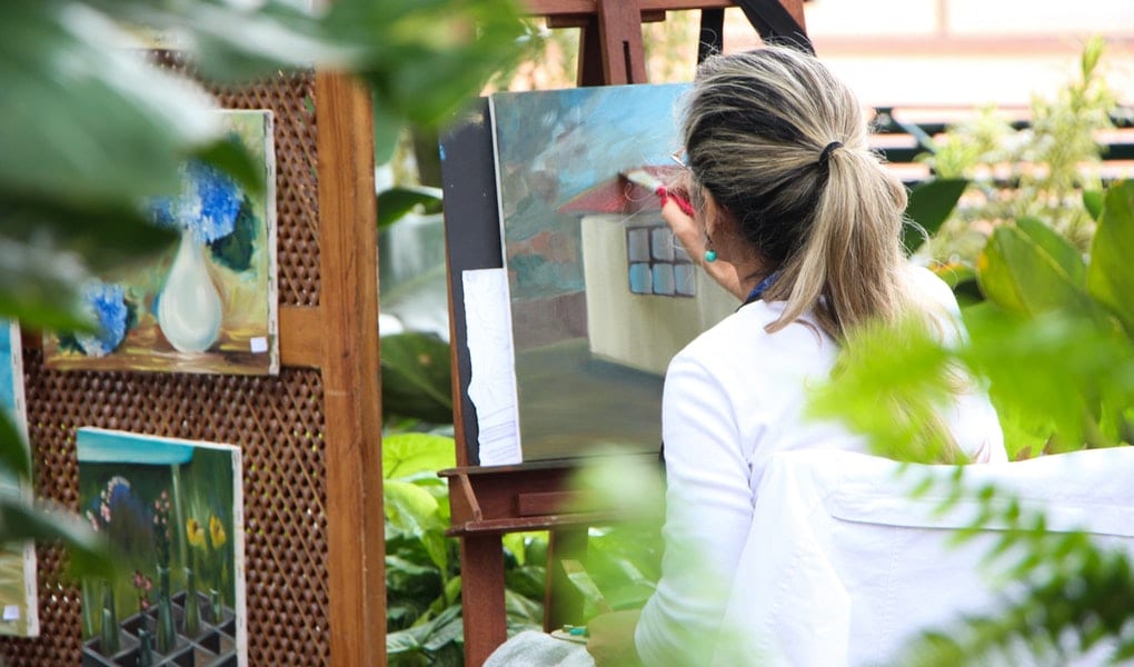 mladá žena maľuje obrazy vo svojej zelenej záhrade