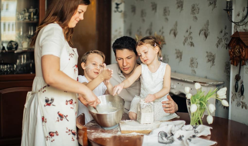 mladá rodinka spoločne pecie nedelný koláč a všetci sa pri tom bavia